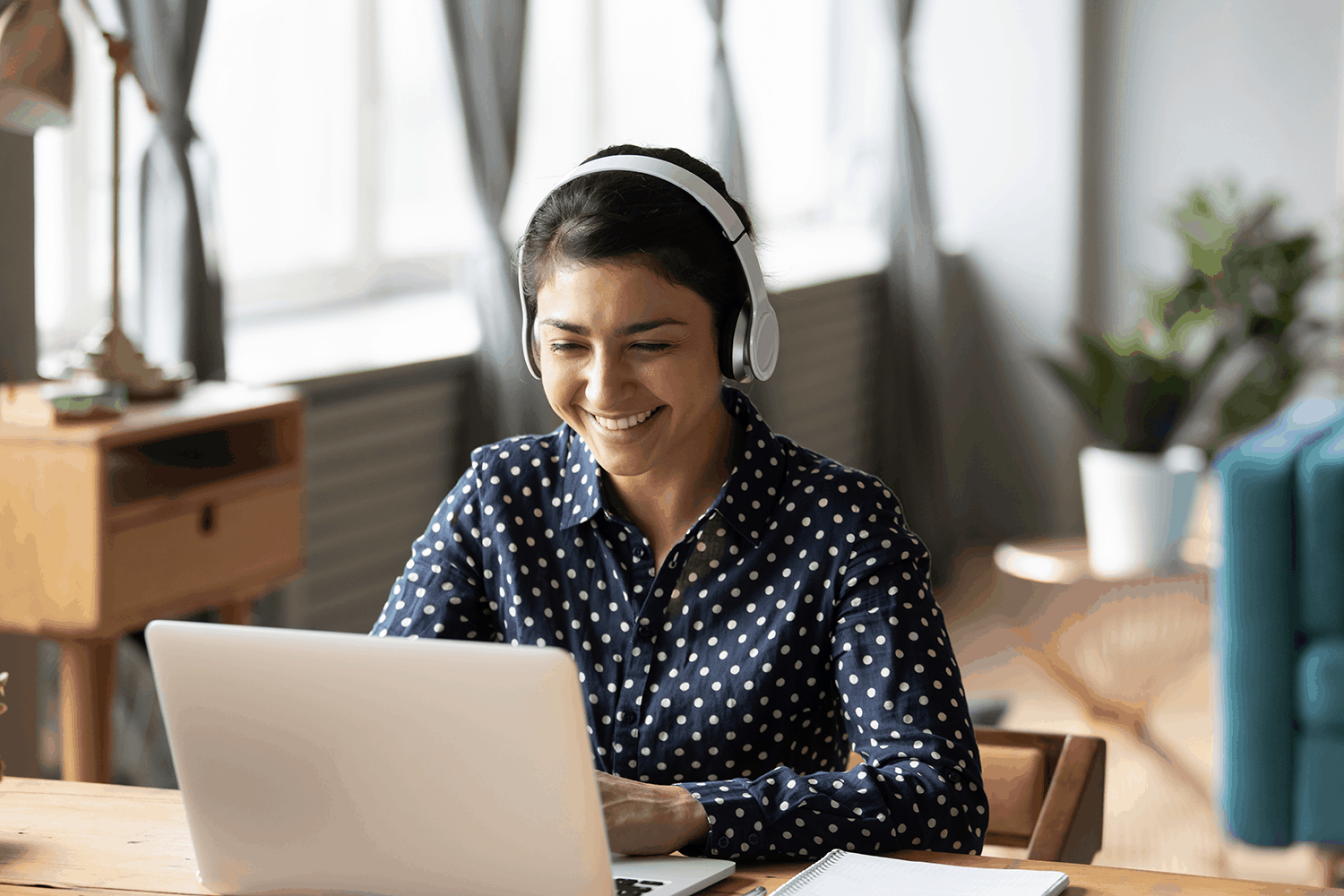 Woman wearing headphones working on a computer and smiling because she finds her IT career very fulfilling