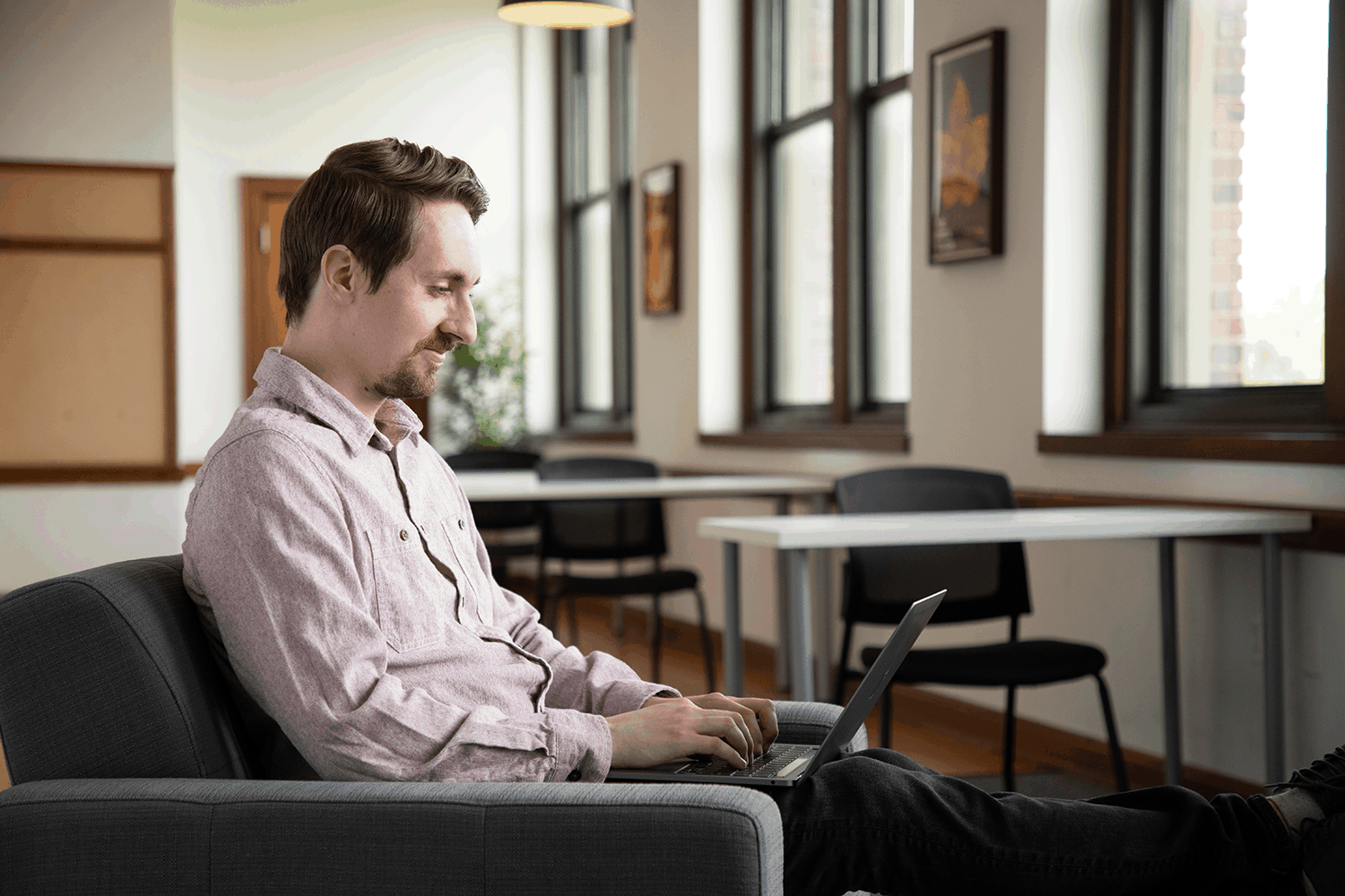 Man sitting in a chair working on his laptop excited for his IT career training