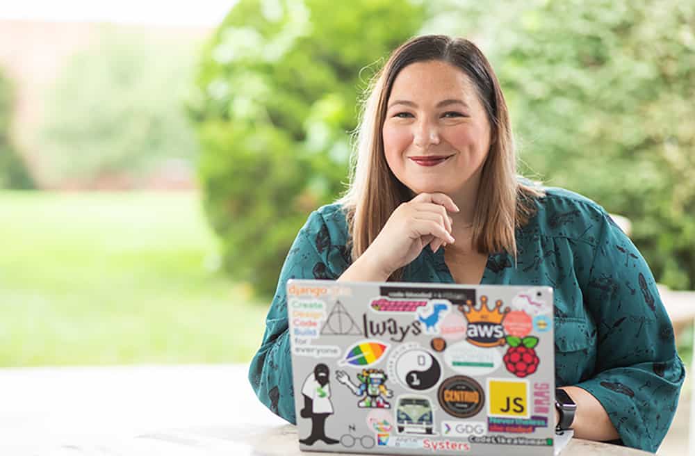 Woman working on virtual training on a laptop with so many stickers on it, you gotta admire she went well above the minimum required pieces of flair