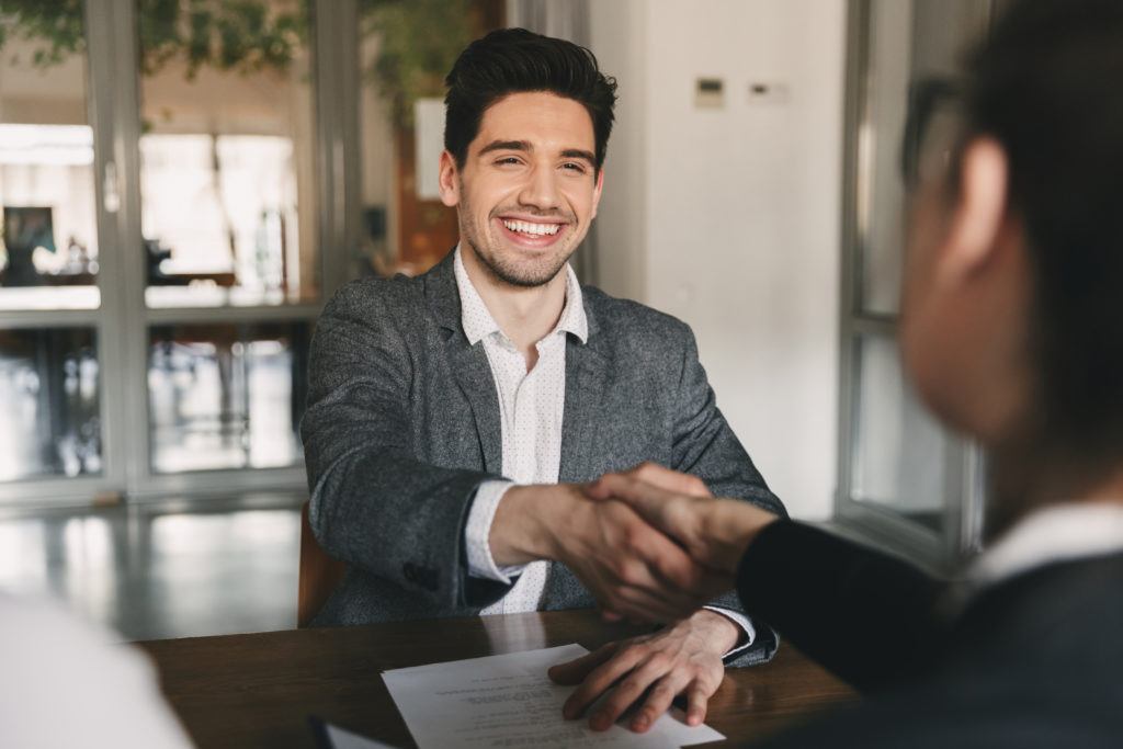 Man in business suit shaking hands with someone across the table