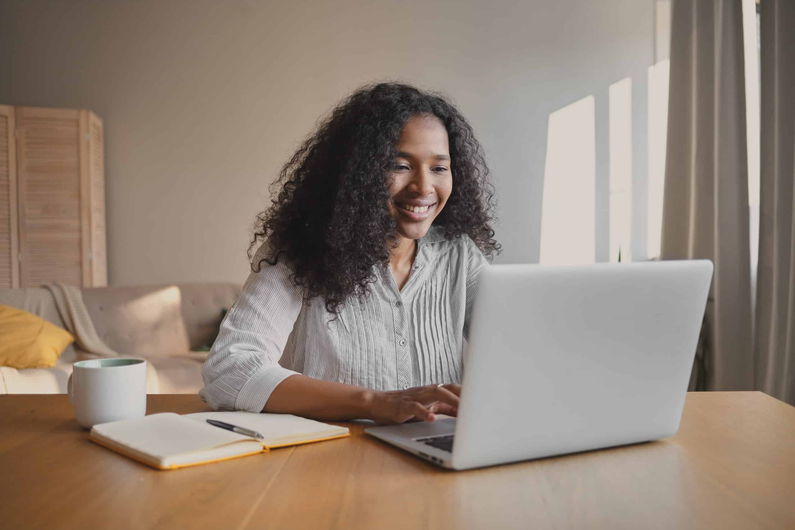 Cheerful woman working on laptop excited for her new IT career