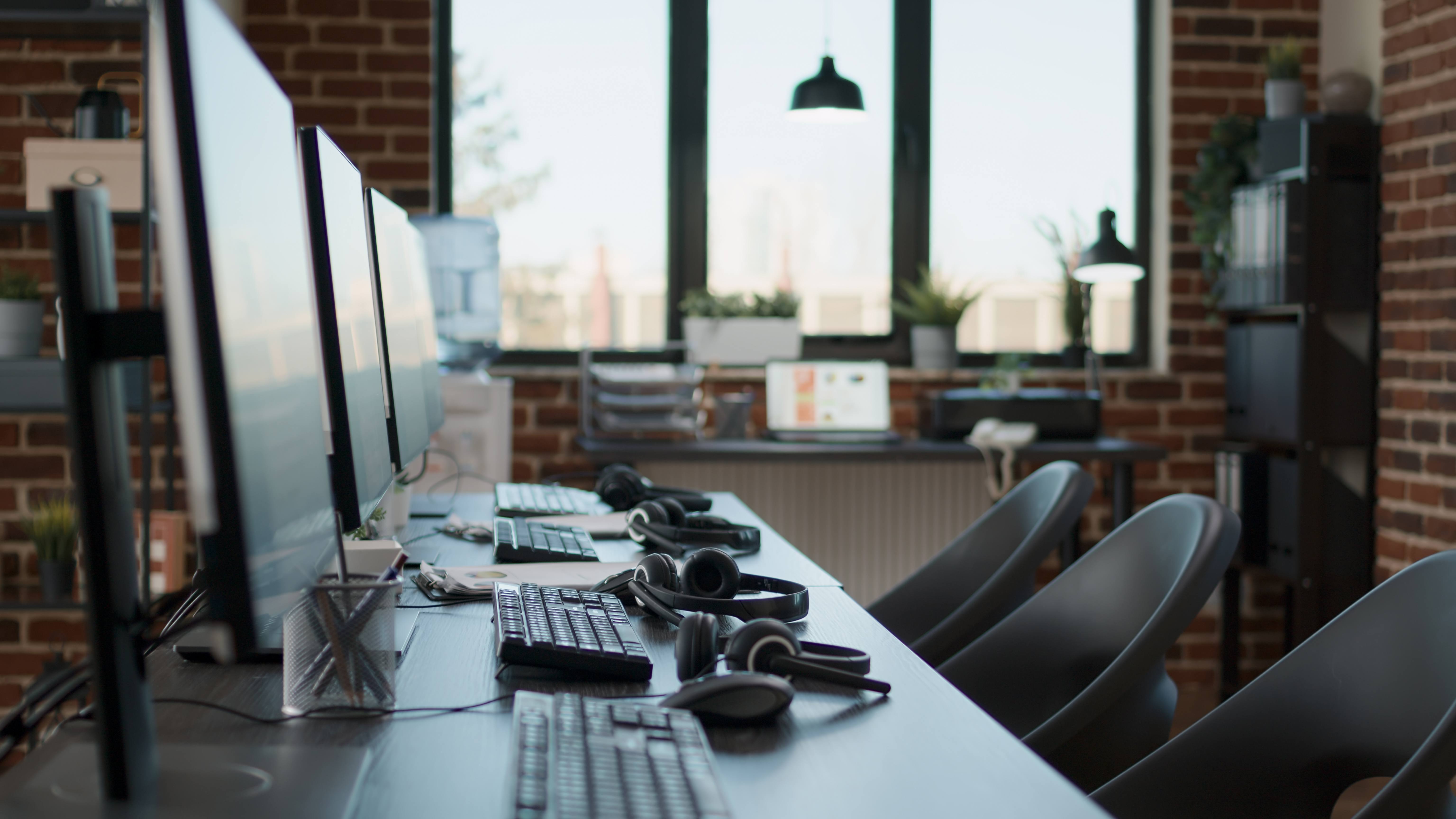 Desk with multiple computers and headsets. No people