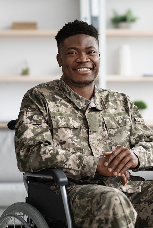 Smiling African American army veteran, wearing fatigues and sitting in a wheelchair